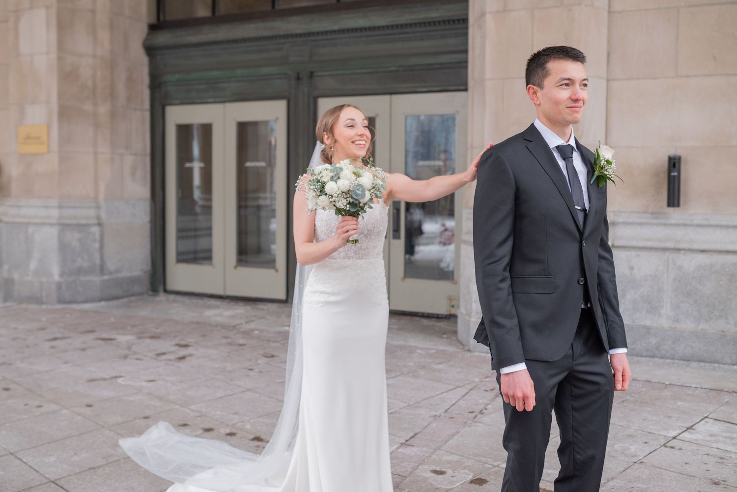 Bride and groom share joyful first look in front of Château Laurier in winter
