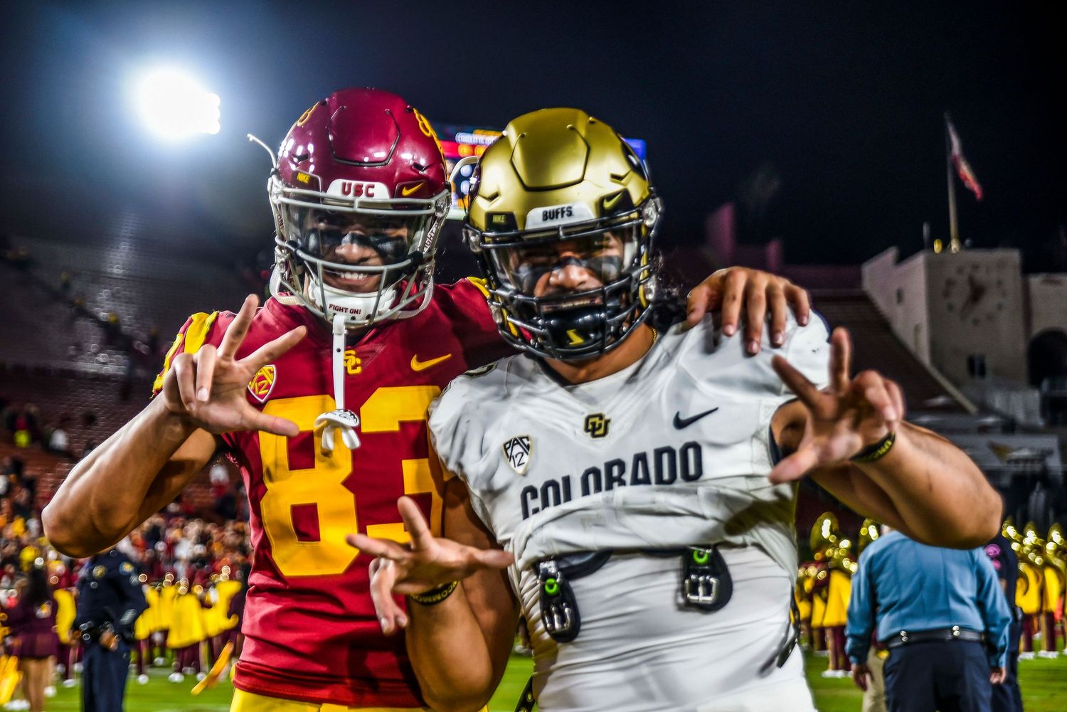 USC and Colorado football players celebrating after a play under stadium lights.