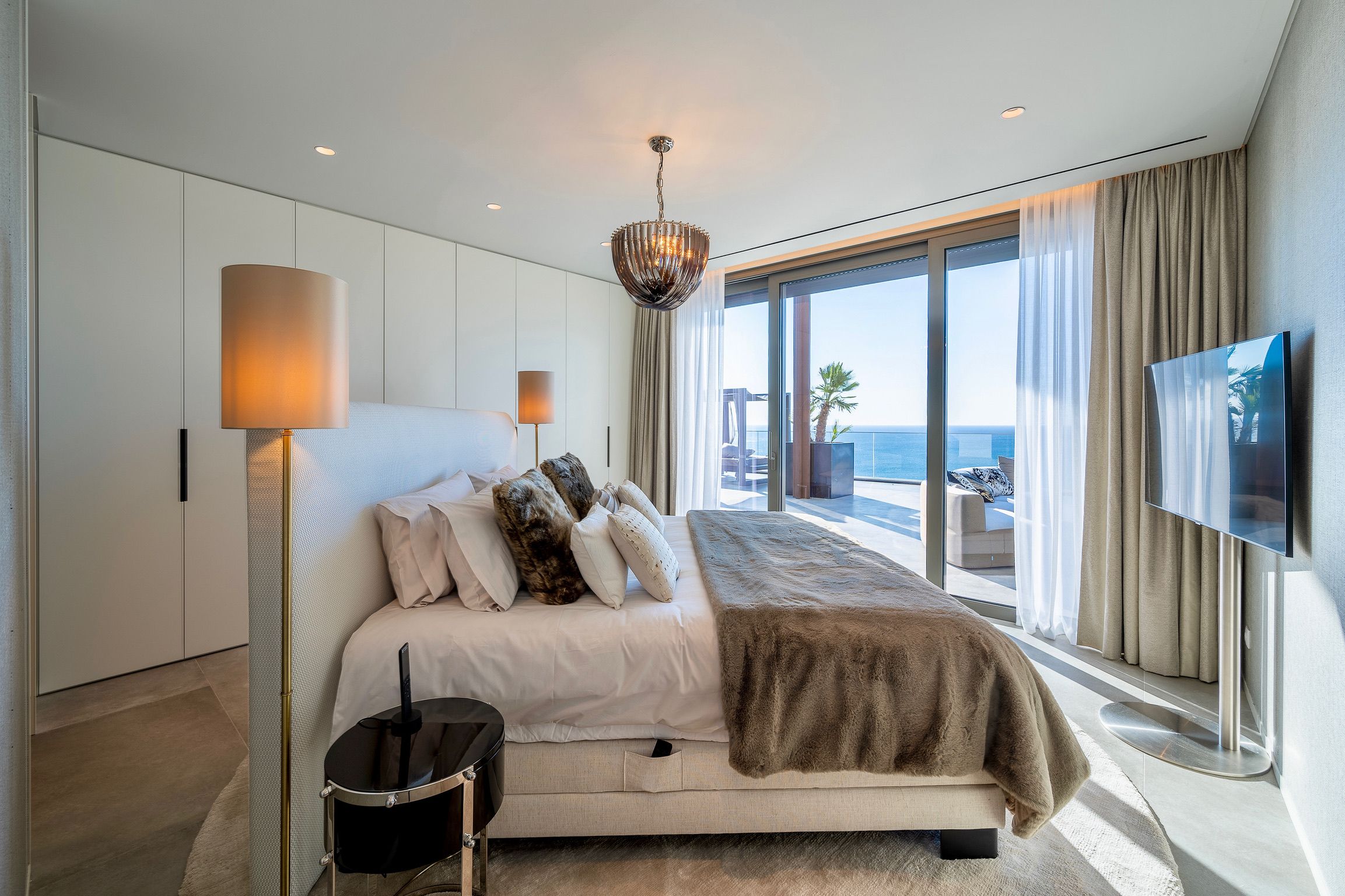Luxurious bedroom with panoramic windows offering stunning ocean views in the Algarve by Parallel Studios