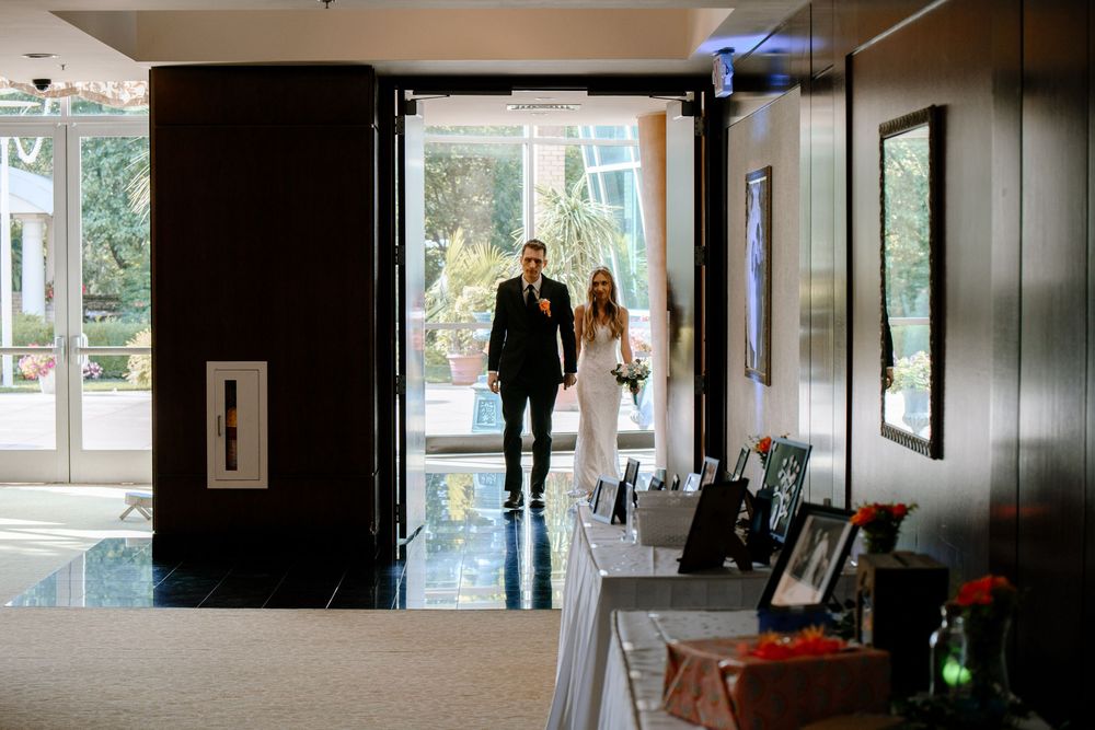 Dimly lit interior hallway with artwork on walls and natural light streaming through windows at the end of corridor.