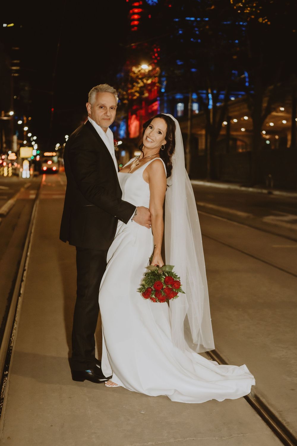 A romantic nighttime wedding photo shows the couple posing on city streets with red and blue lighting.