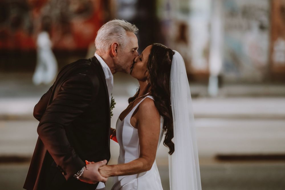 A romantic outdoor wedding celebration shows loving couples sharing intimate moments together at sunset.