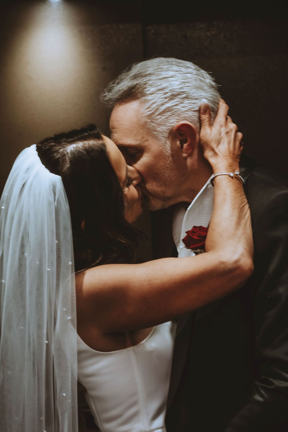 A romantic series of wedding photos showing a couple sharing intimate kisses in a dark, moody setting with flowing white veil.