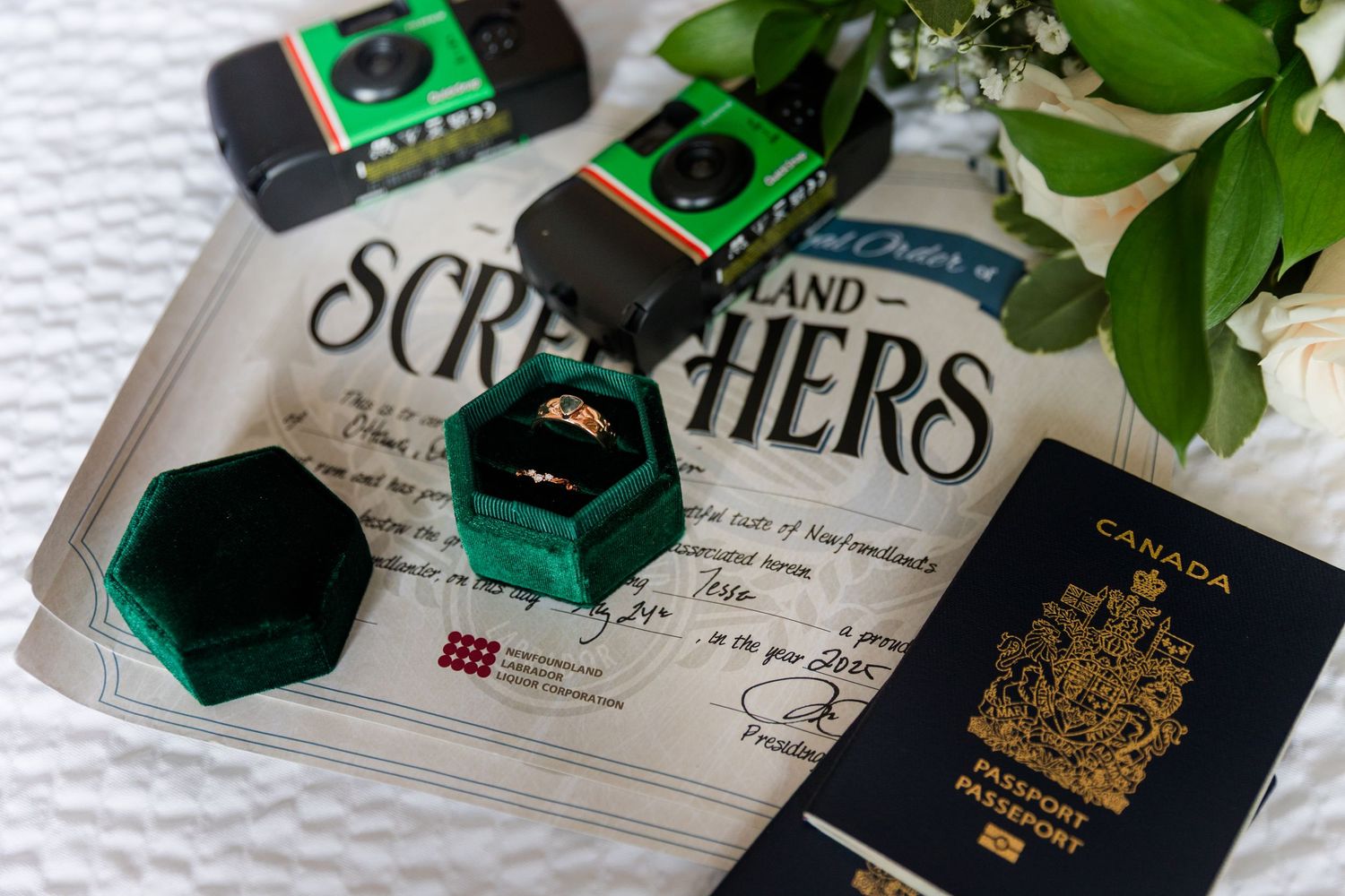 Rolls of exposed film and vintage camera accessories arranged with a Canadian passport and sheet music on white fabric.