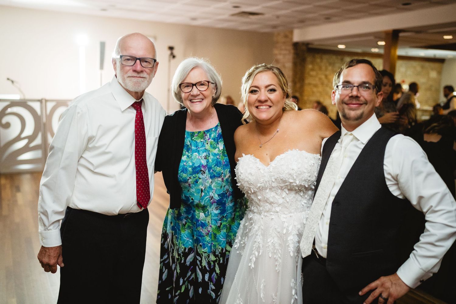 A group of wedding guests smile together during a reception celebration.