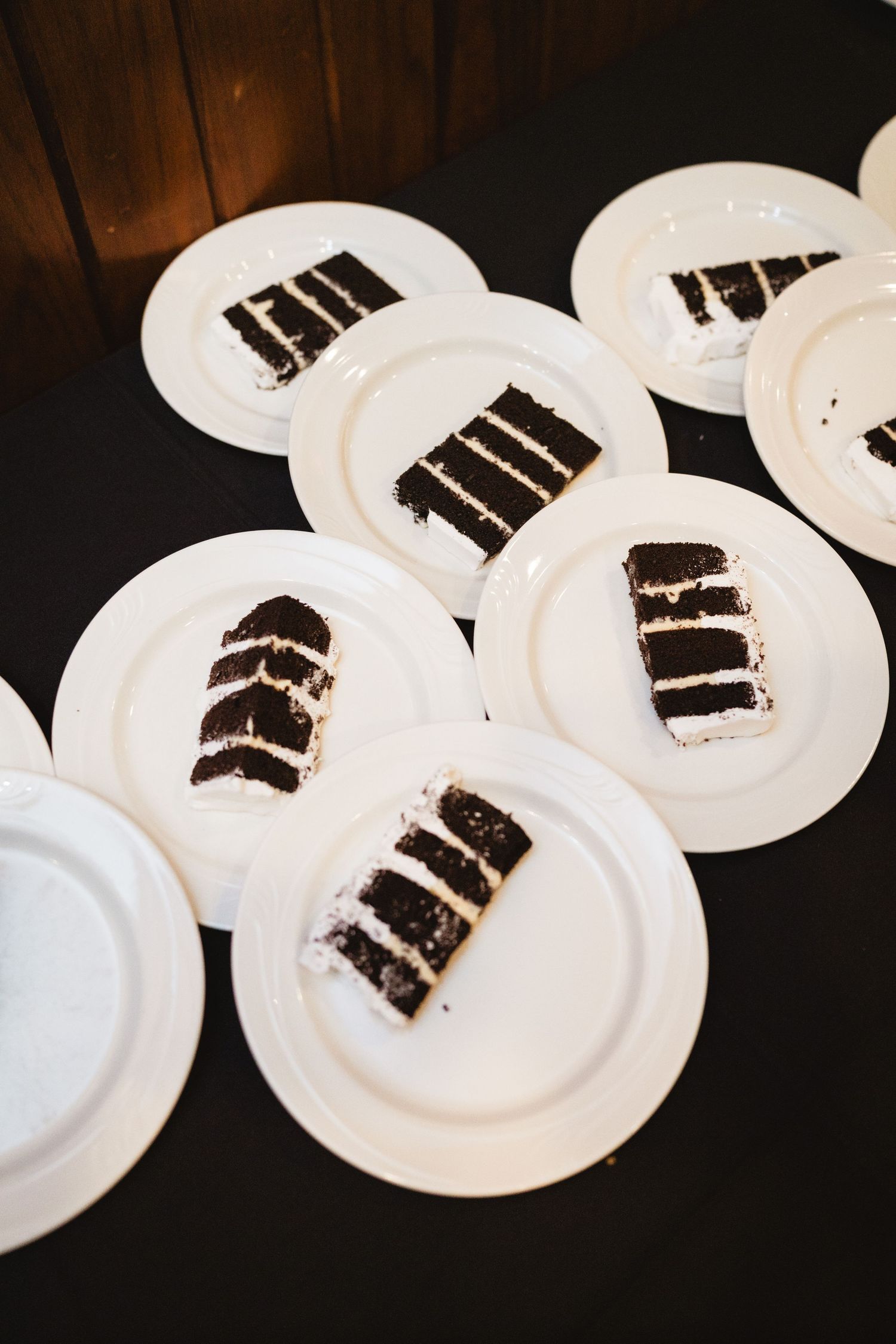 Black and white plated desserts arranged on a dark table at a wedding reception.