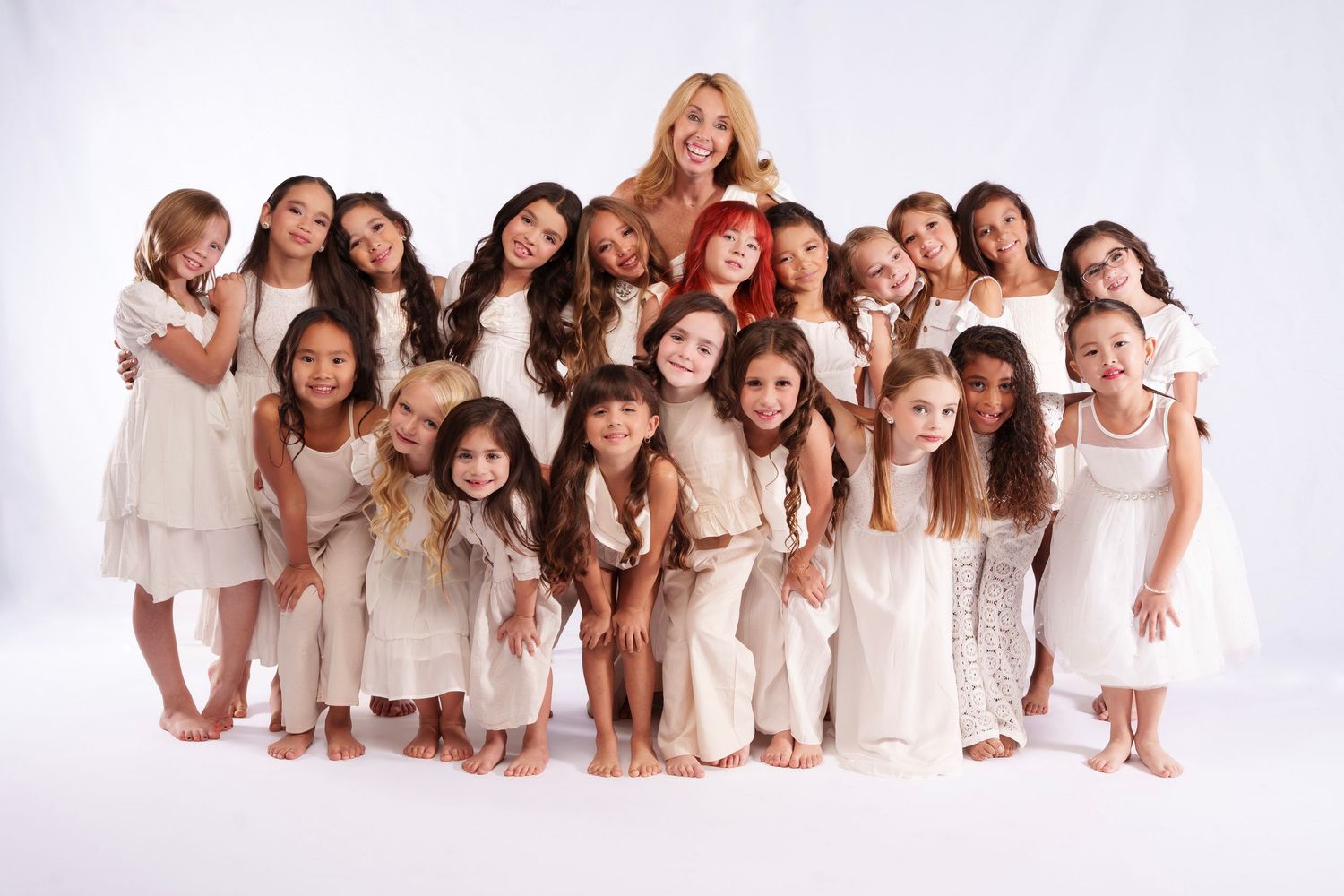Group portrait of women in white dresses lying down in studio setting.