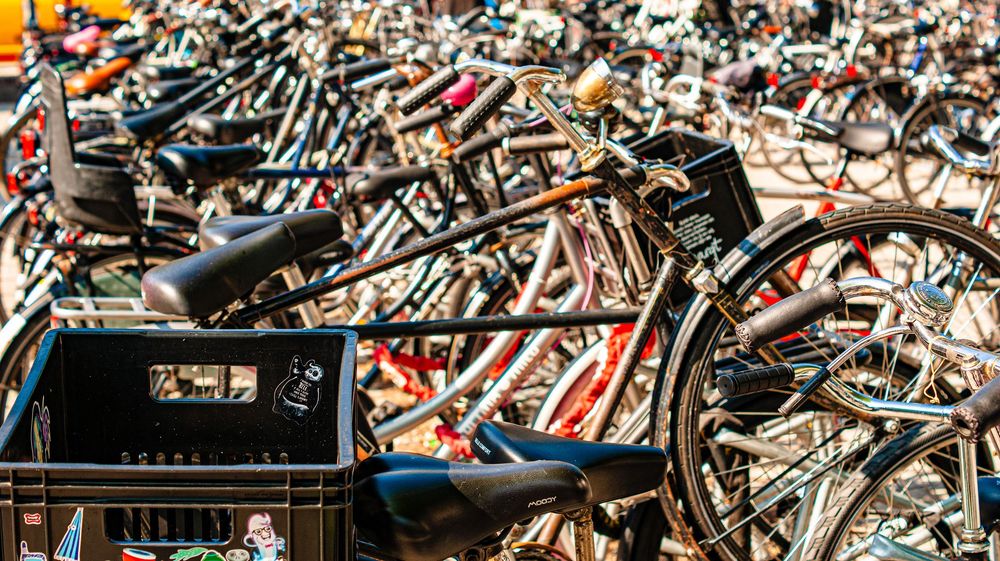 Dense cluster of parked bicycles creates abstract pattern of wheels and frames.
