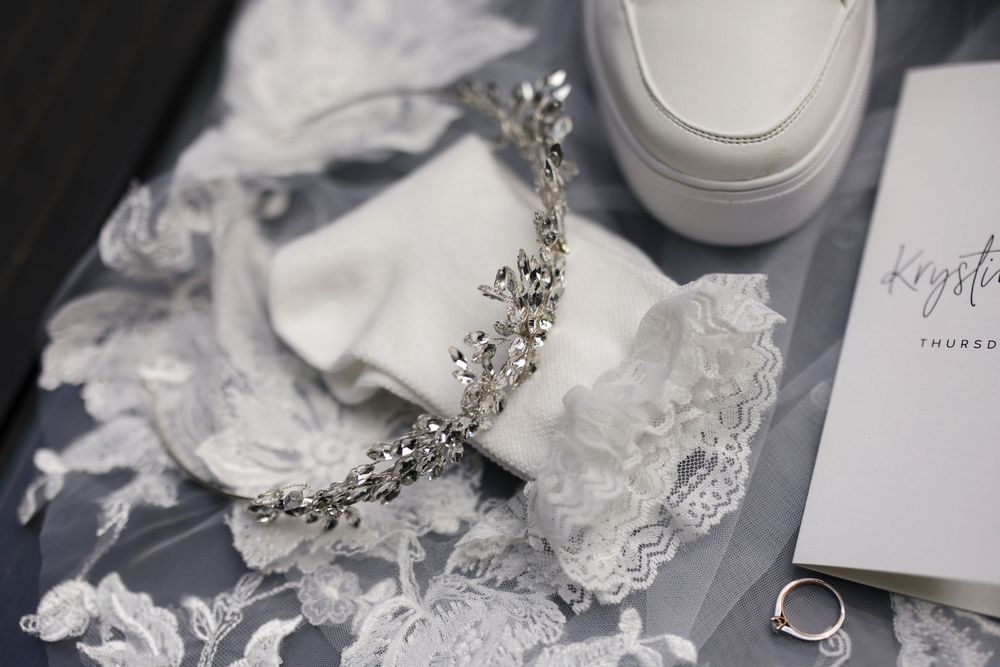 Elegant bridal jewelry and accessories arranged on gray surface with white fabric details.