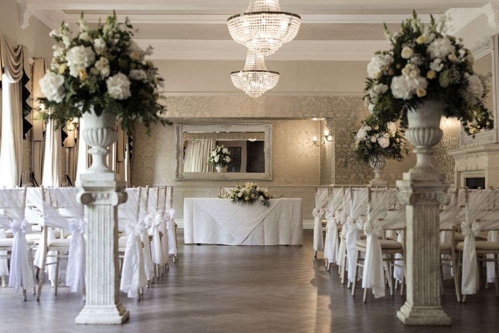 Elegant wedding venue with crystal chandeliers and white floral arrangements.