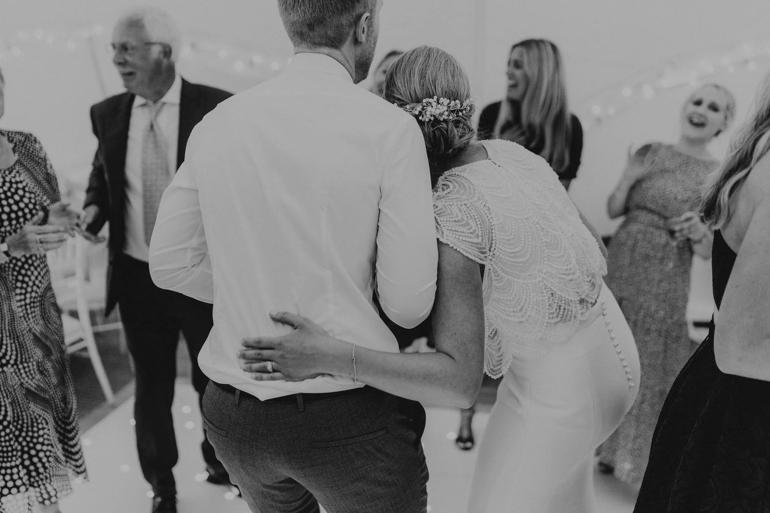 Wedding guests dance and celebrate together on a lively dance floor during an evening reception celebration.