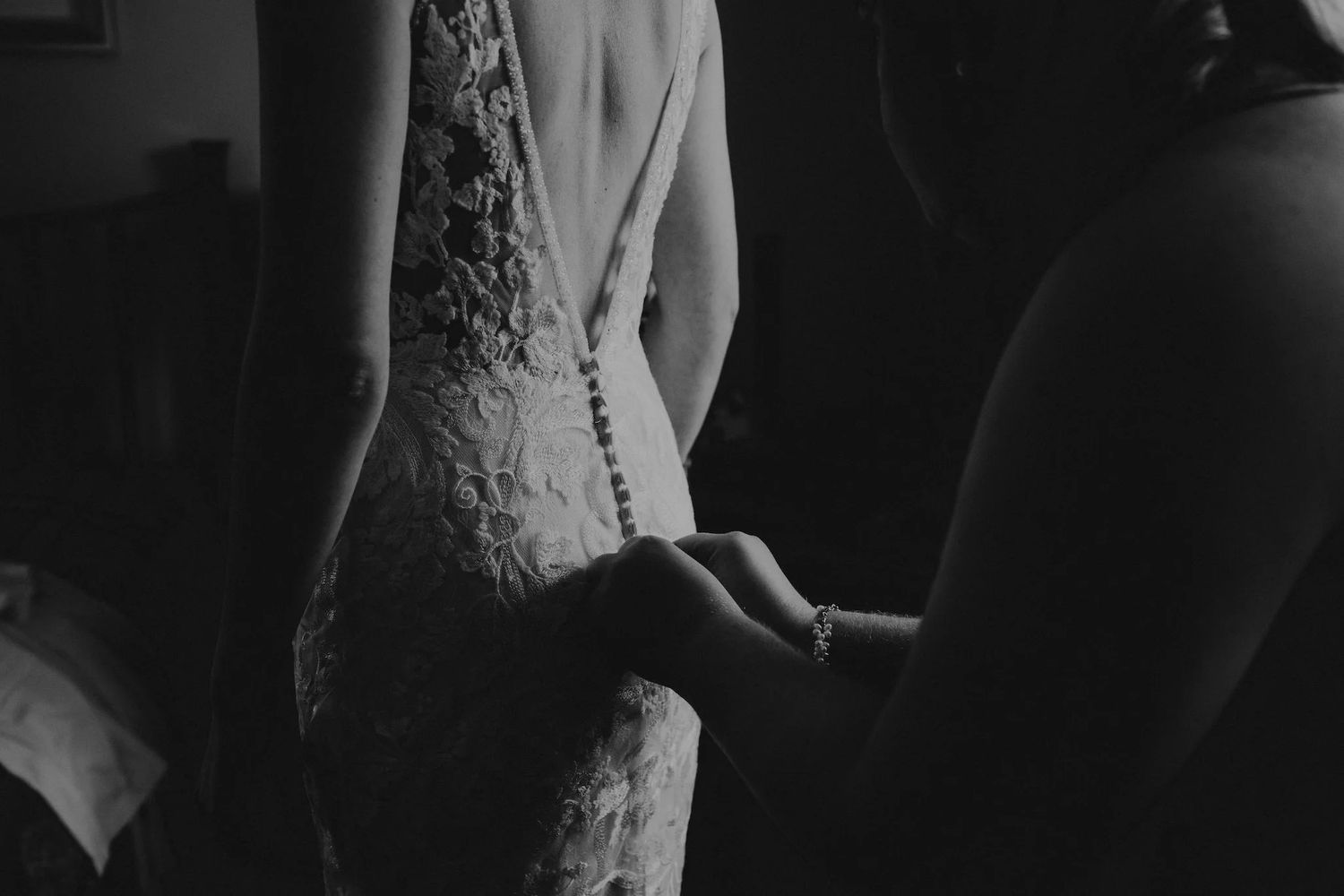 Artistic black and white images capturing intimate wedding moments in dark, moody lighting.