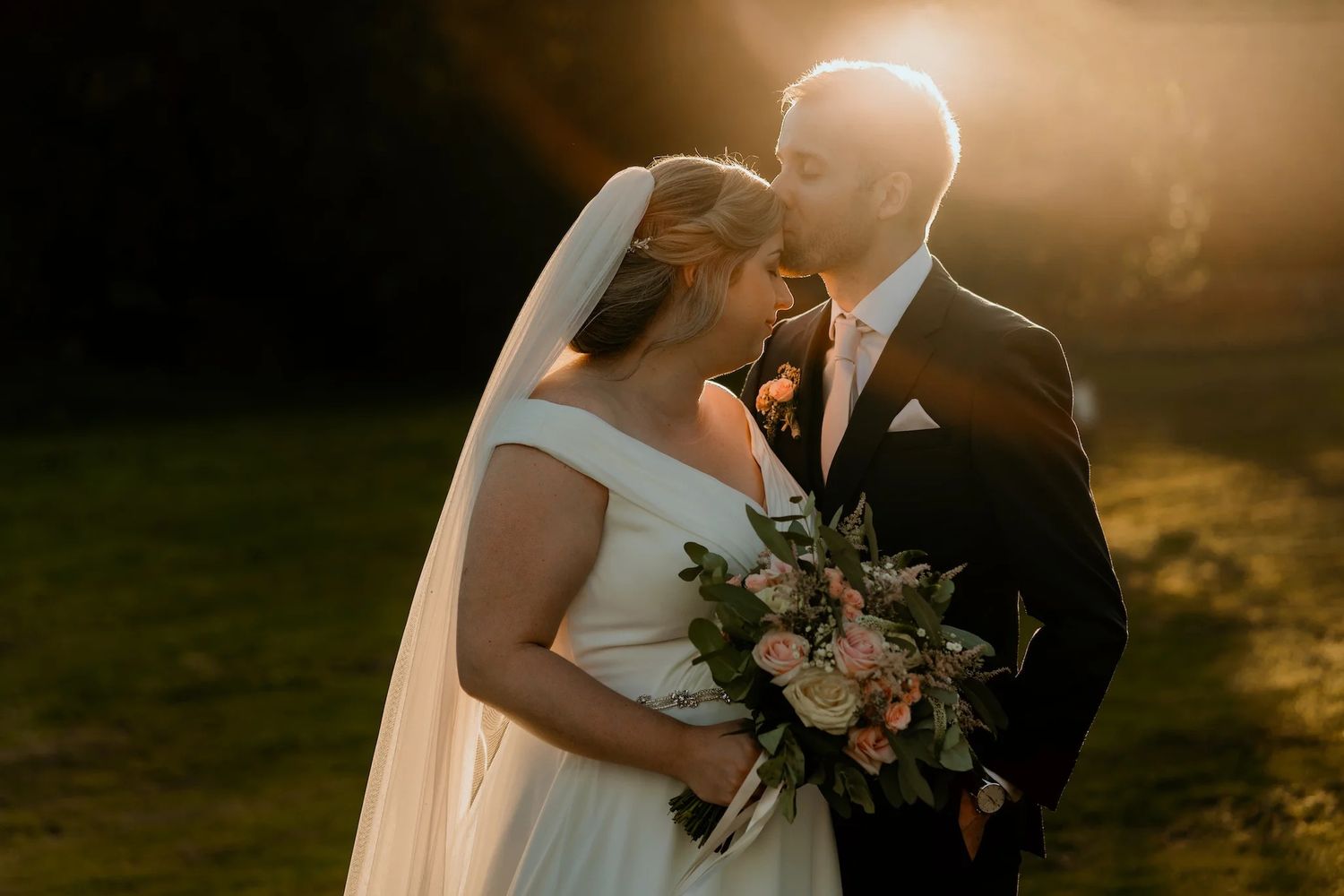 Golden hour wedding portraits with warm sunset lighting and soft focus silhouettes.
