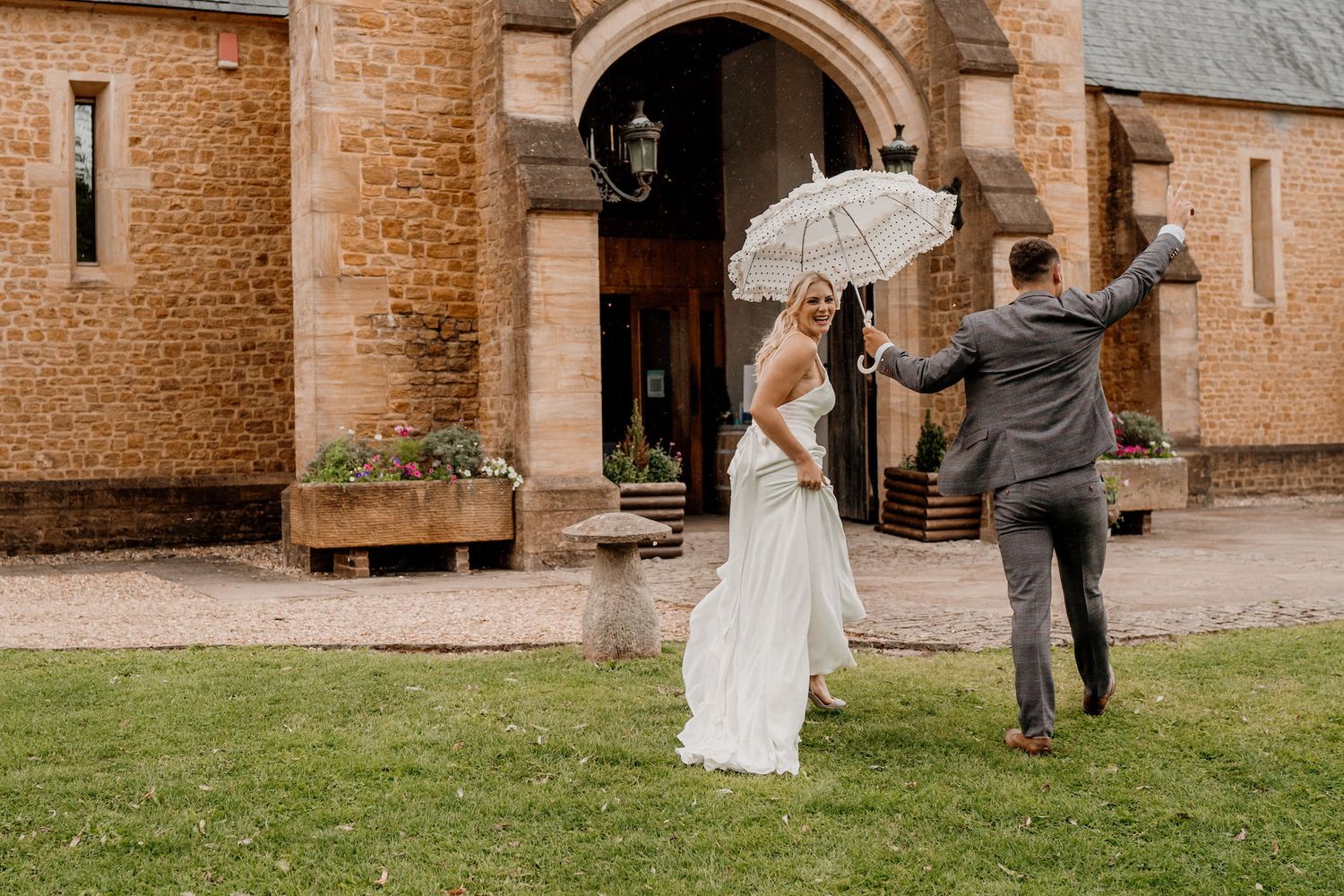 A couple dances together in front of a rustic brick building with beautiful natural lighting.