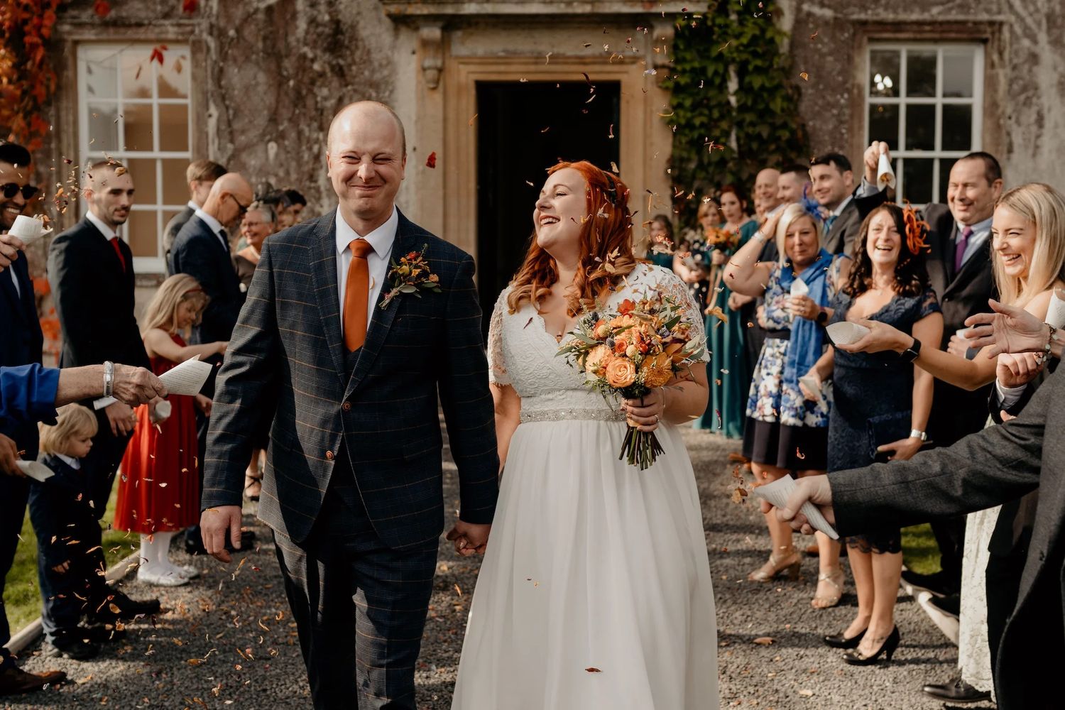 Wedding celebration outside a historic stone building with guests gathered for the ceremony.
