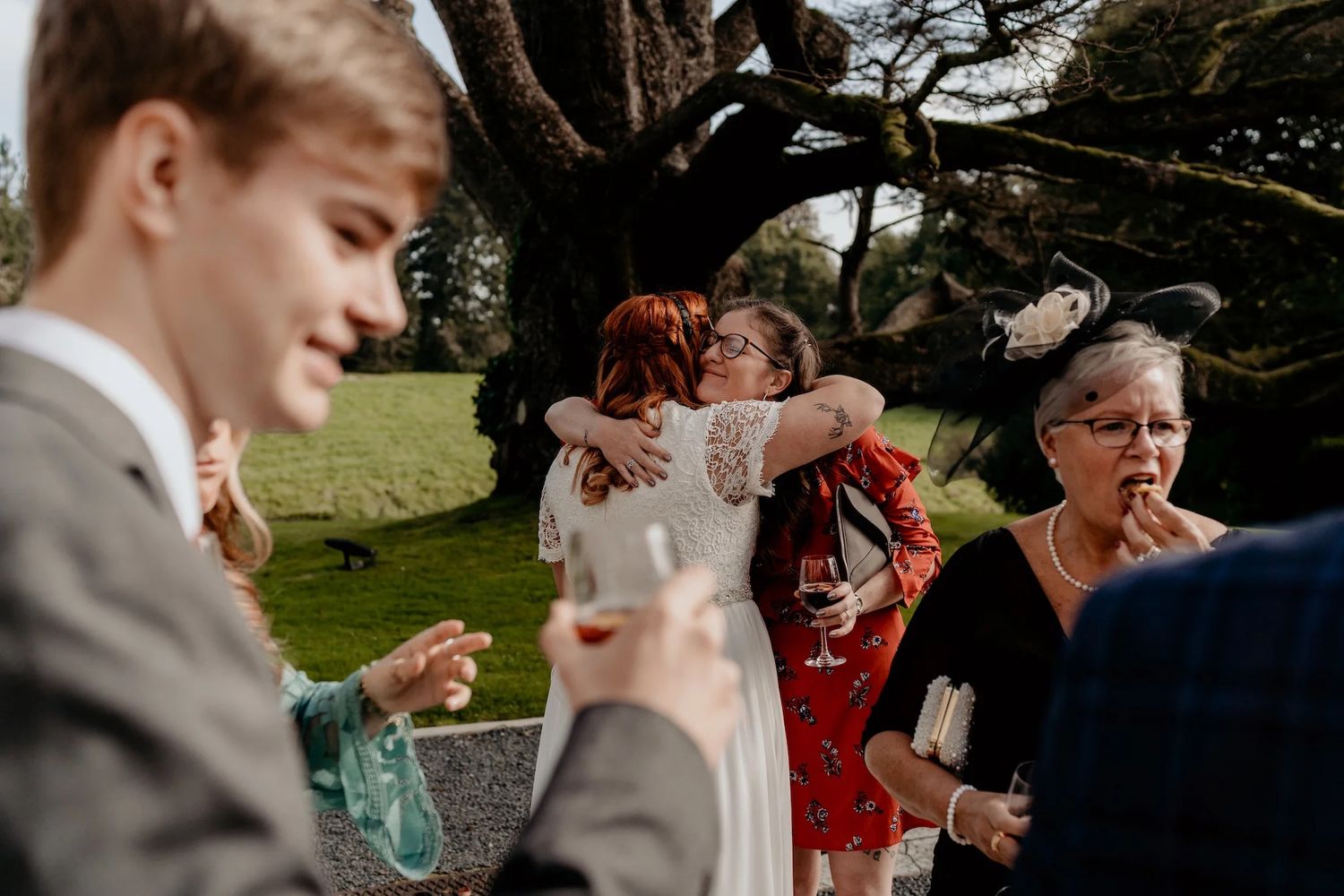Wedding party joyfully throwing confetti in a celebratory moment outdoors in a park.