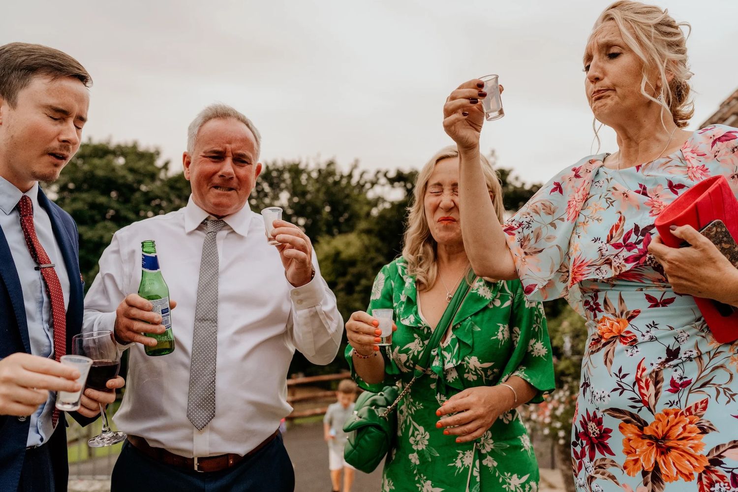 Wedding guests enjoying drinks and conversation outdoors in colorful attire.