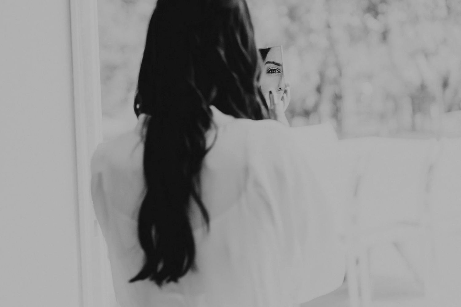 Black and white artistic photo showing long dark hair against white wall.