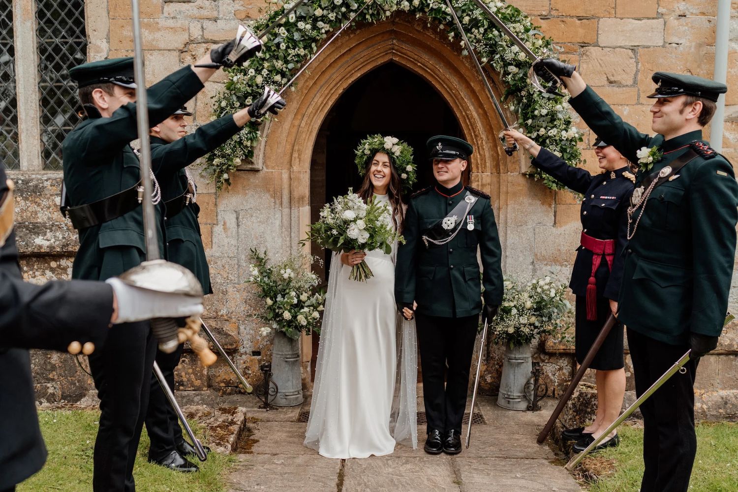 Wedding party celebrating with sparklers outside a rustic stone venue during golden hour.
