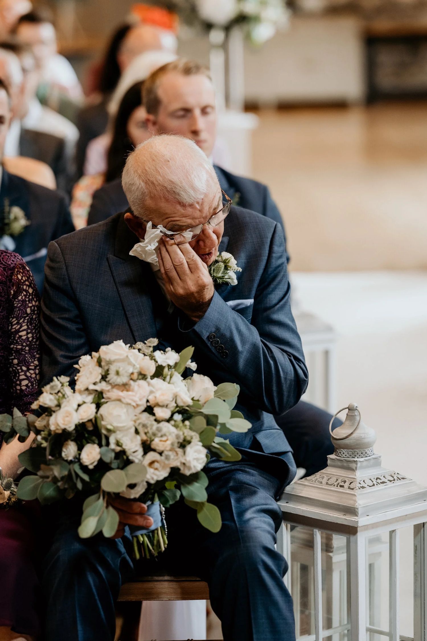 Emotional wedding ceremony moments captured with white floral arrangements and lantern decor.