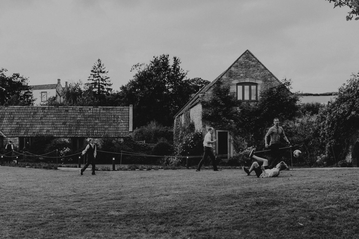 Outdoor wedding venue scene with rustic buildings and lawn set against a rural backdrop.