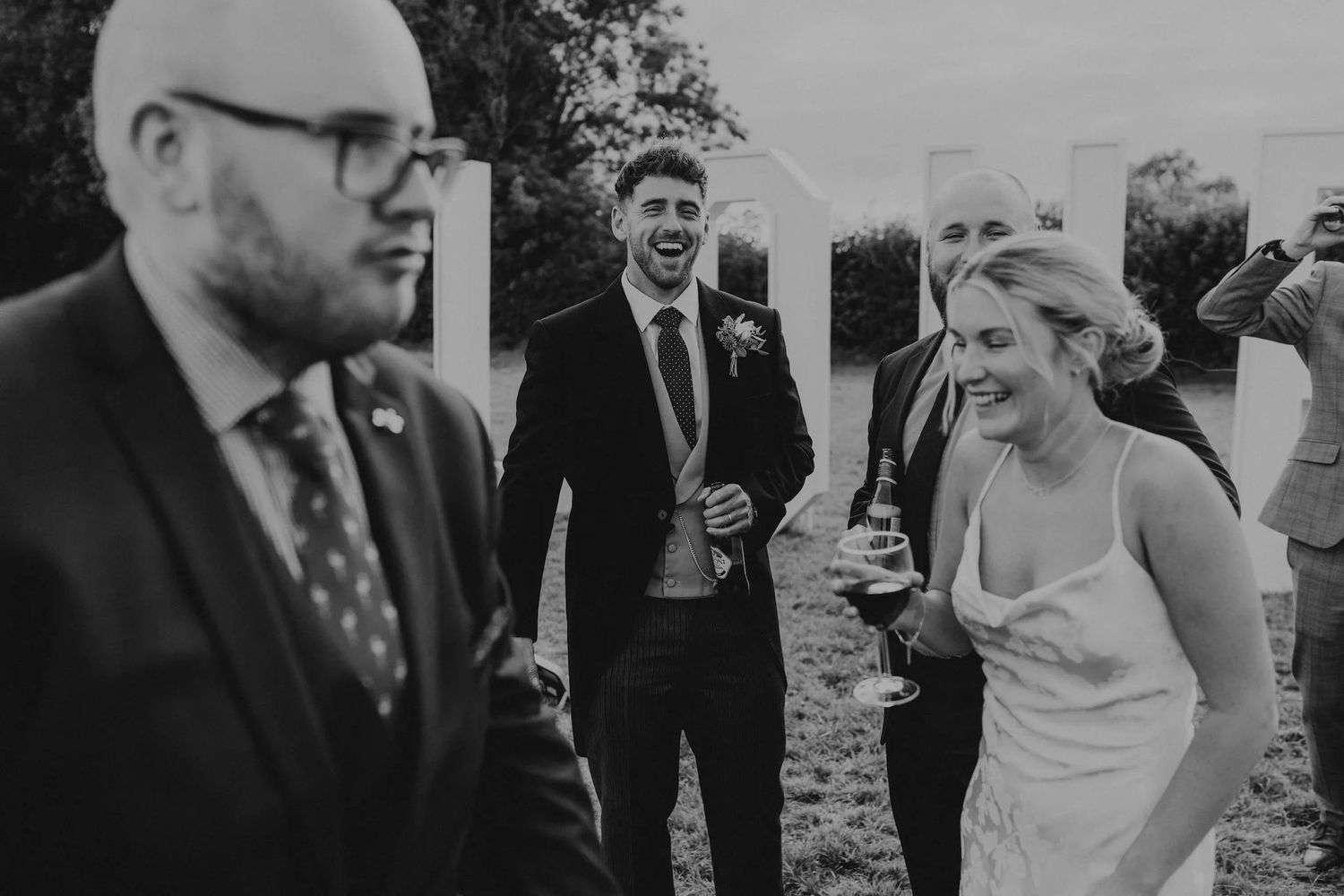 Wedding party members mingle during an outdoor cocktail reception.