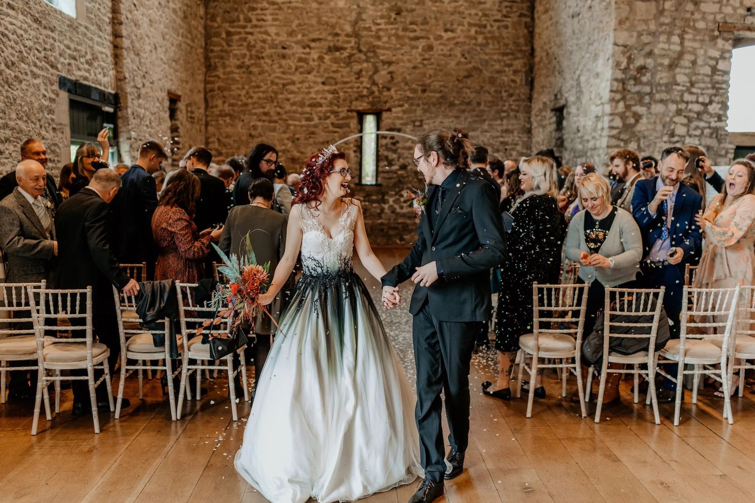 Interior of rustic stone barn wedding venue with white chairs set up for ceremony.