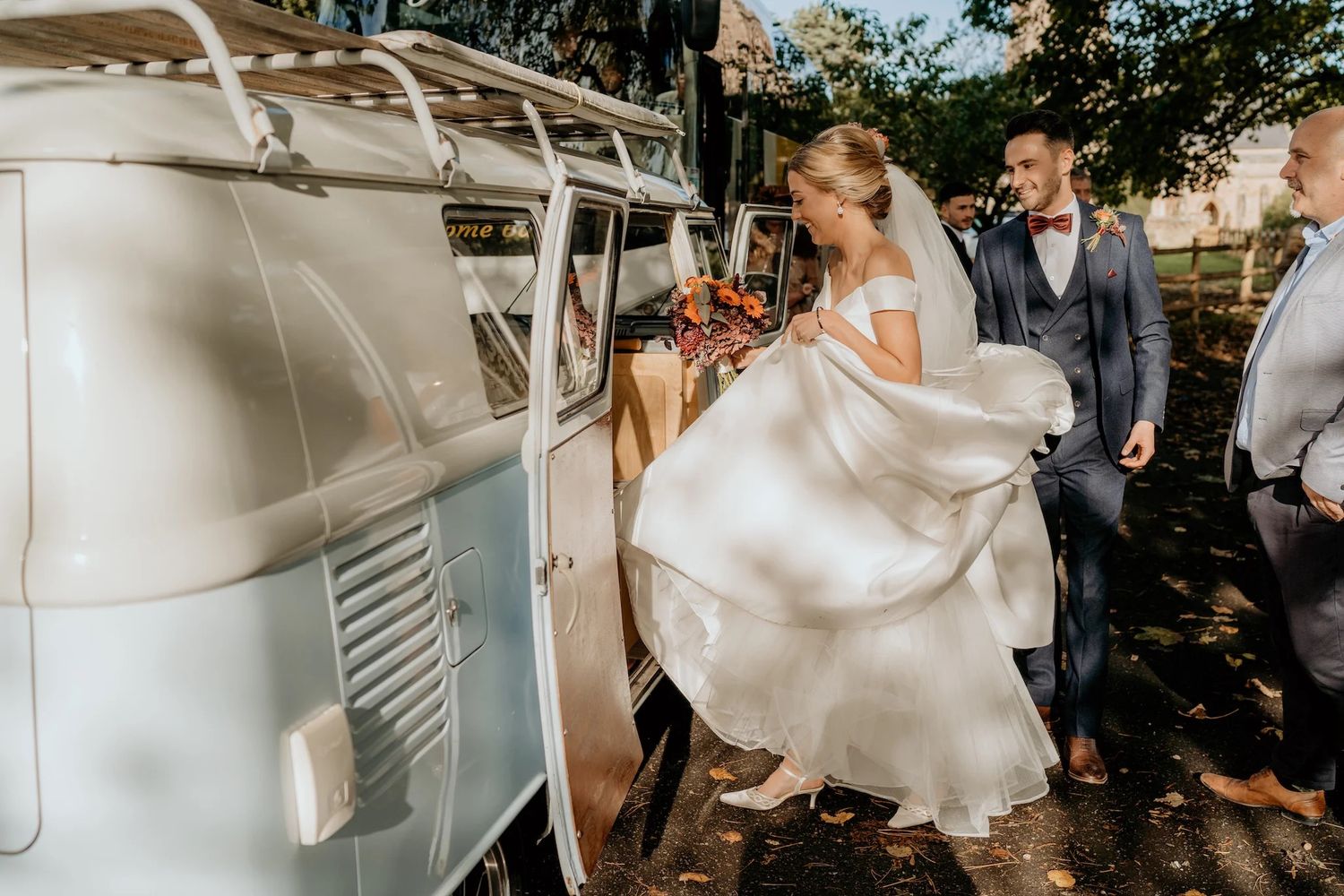 Wedding ceremony outdoors with flowing white dress and guests celebrating in natural sunlight.