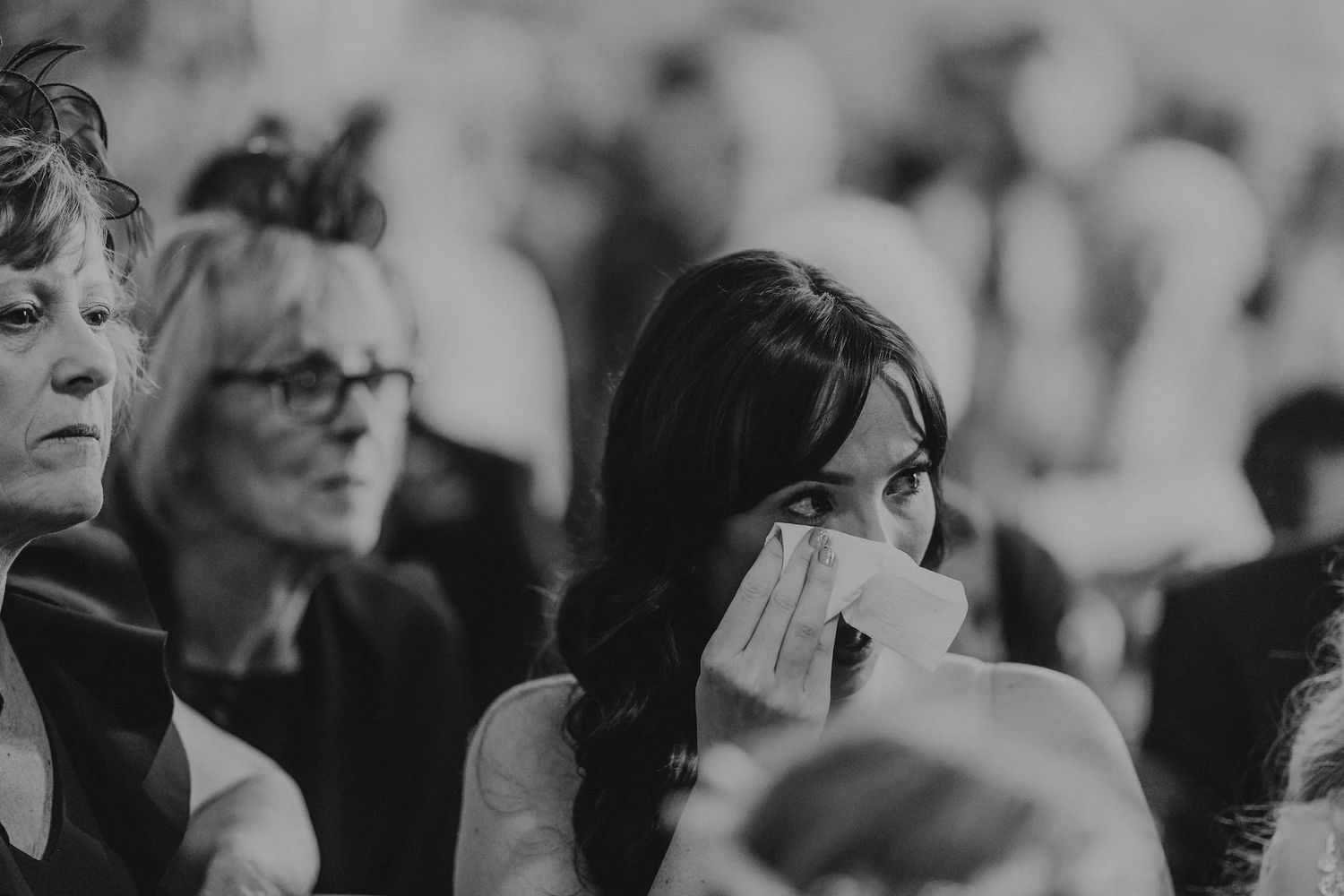 Wedding ceremony audience watching emotional moment in black and white.
