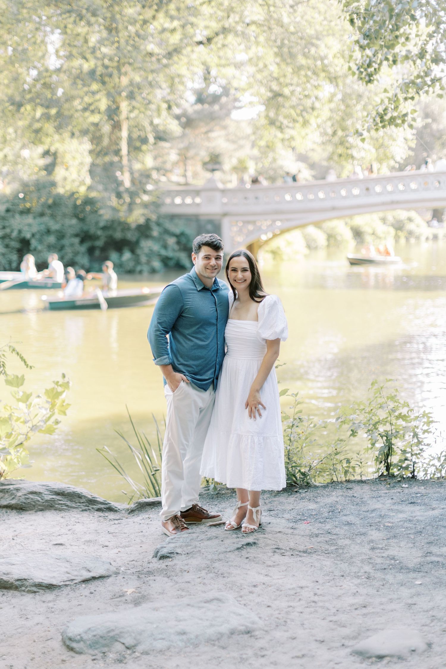 Romantic couple photoshoot by a scenic lake on a sandy beach in natural sunlight.