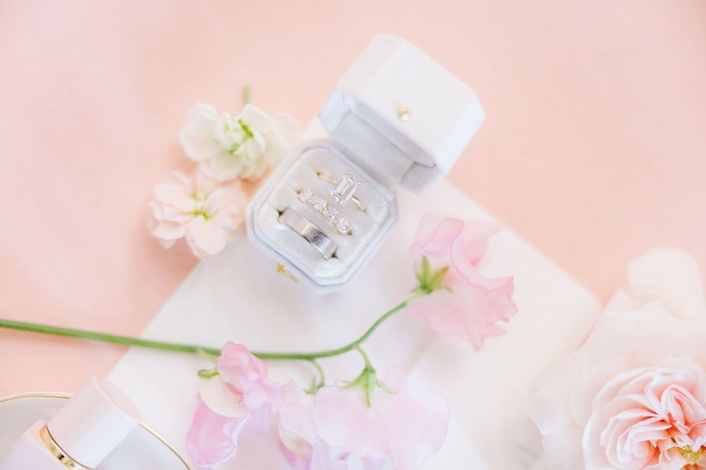 Delicate pink and white flowers arranged with romantic candles and decor on a soft pink background.