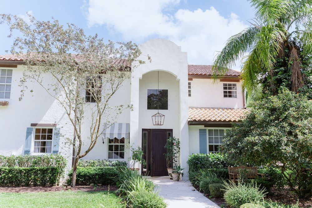 Mediterranean-style white stucco building exterior with palm trees and arched doorways.