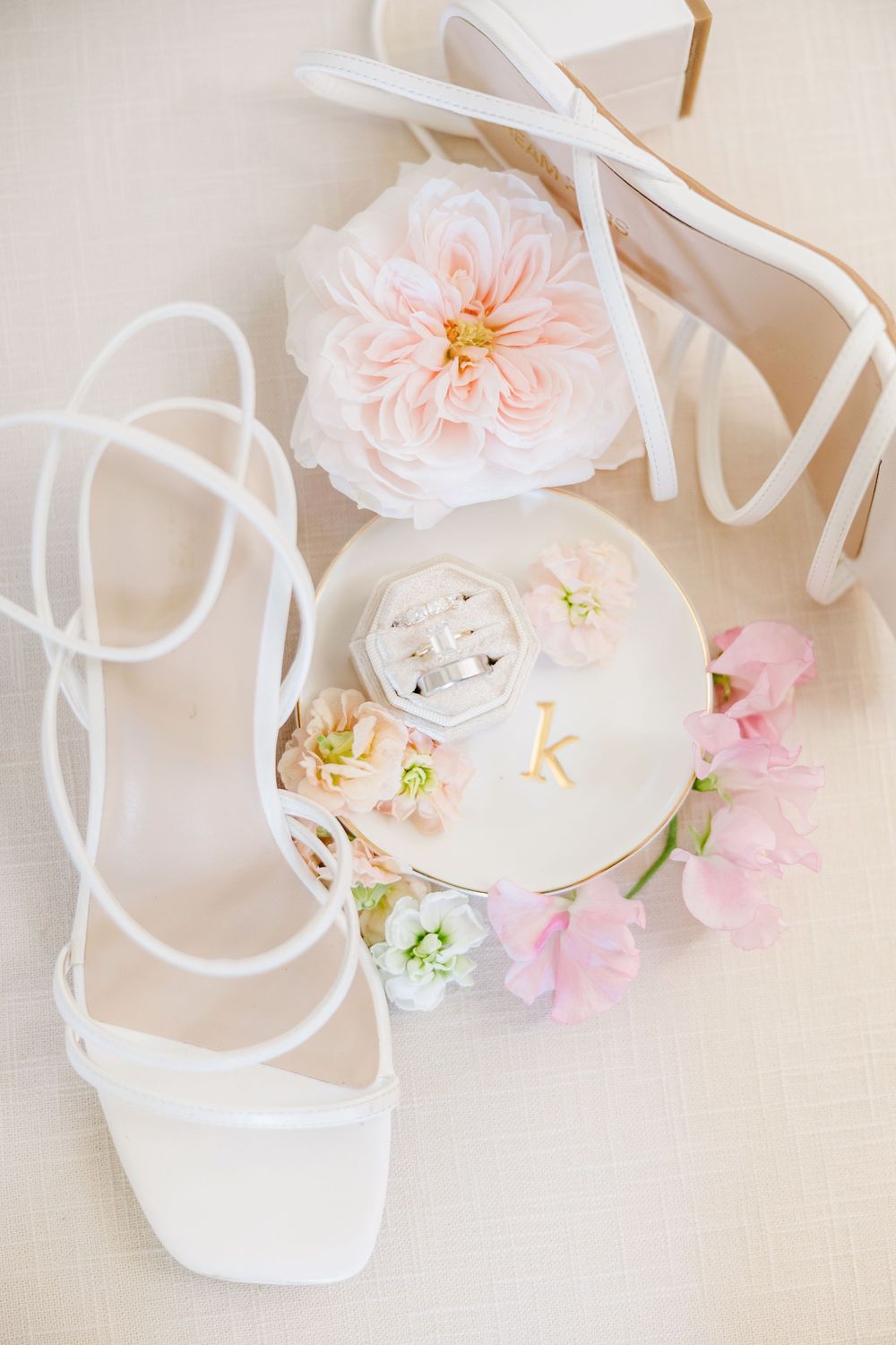 Delicate pink garden roses and white decor elements arranged on a light neutral background.