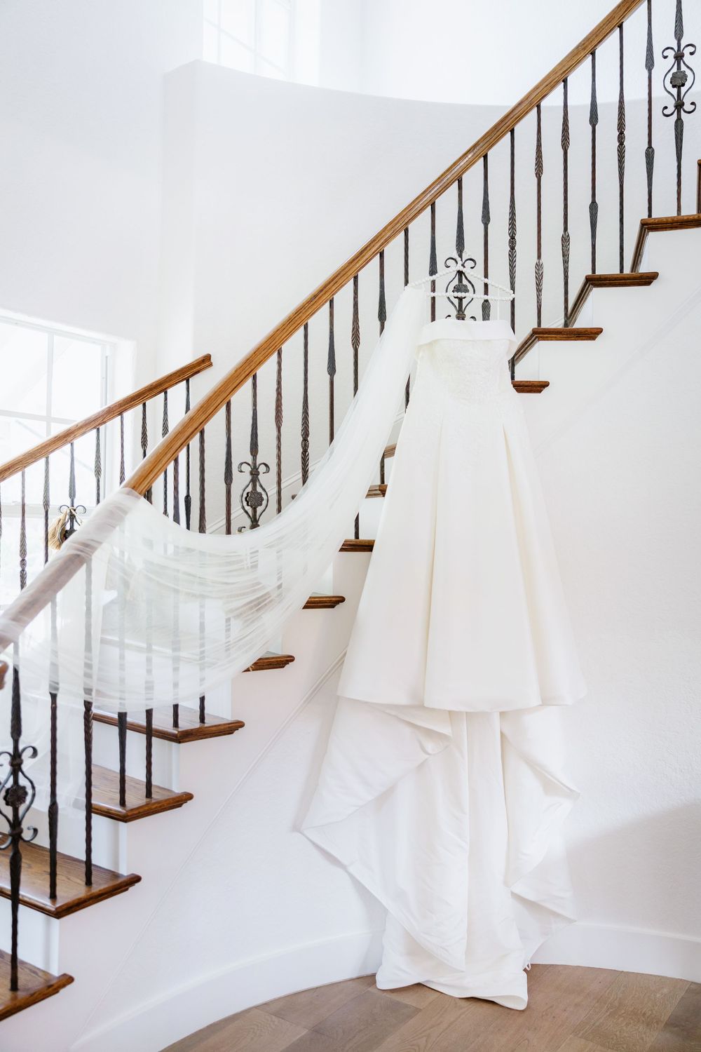 White bridal gown displayed on an elegant staircase with wrought iron railings.