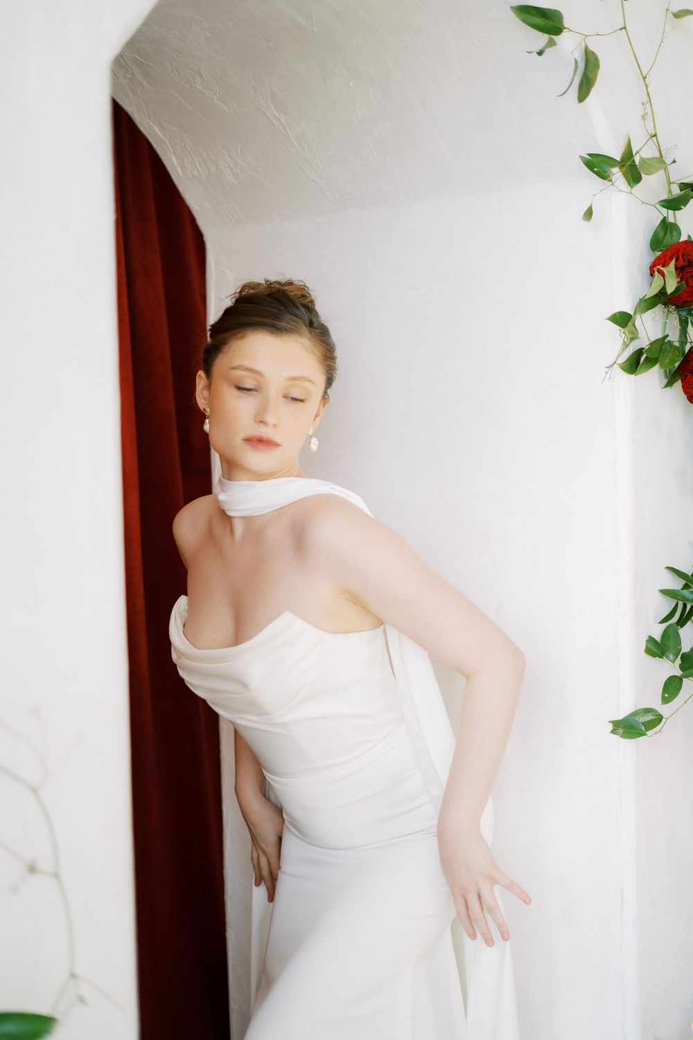 Elegant white draped fabric in a bright minimalist space with red floral accents.