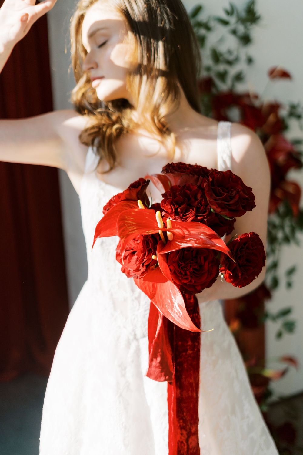 A white wedding dress adorned with vibrant red roses and ribbons creates a striking contrast.