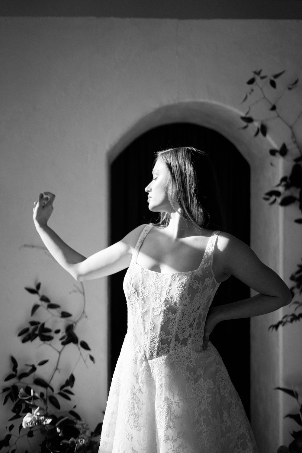 Black and white portraits of someone in a white dress posing dramatically against an arched wall.
