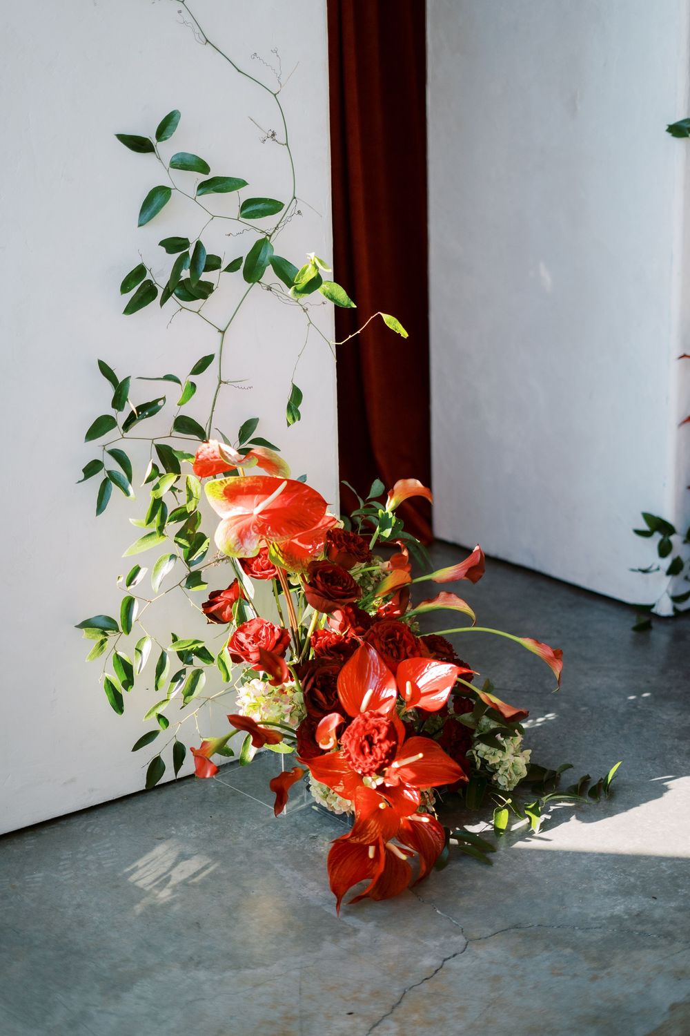 A vibrant arrangement of orange lilies and green foliage sits in the corner against a white wall and wooden trim.