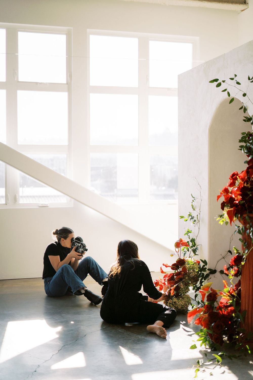 A sunlit room with white walls and arched doorway decorated with orange floral arrangements.