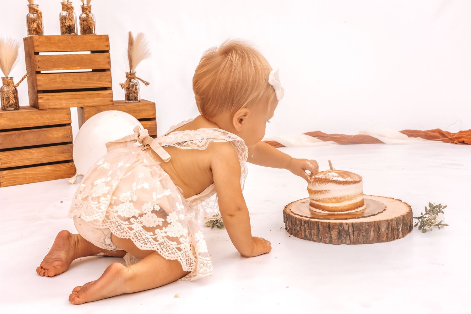 Baby milestone photo collection with wooden props and delicate lace details on white background.