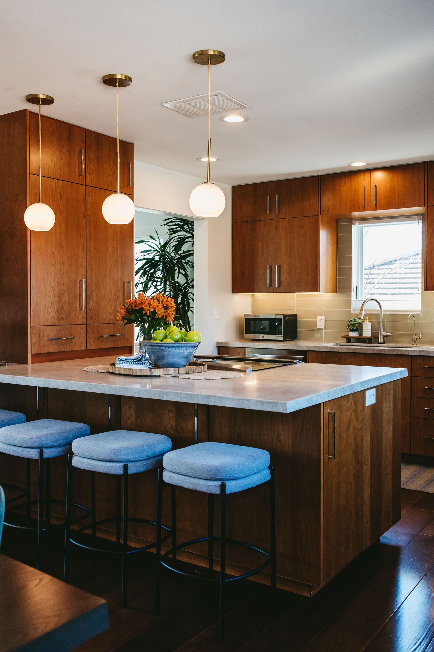 Modern kitchen with warm wood cabinets, linear handle pulls, gold finishing mixed with white gold finishes, and granite countertops