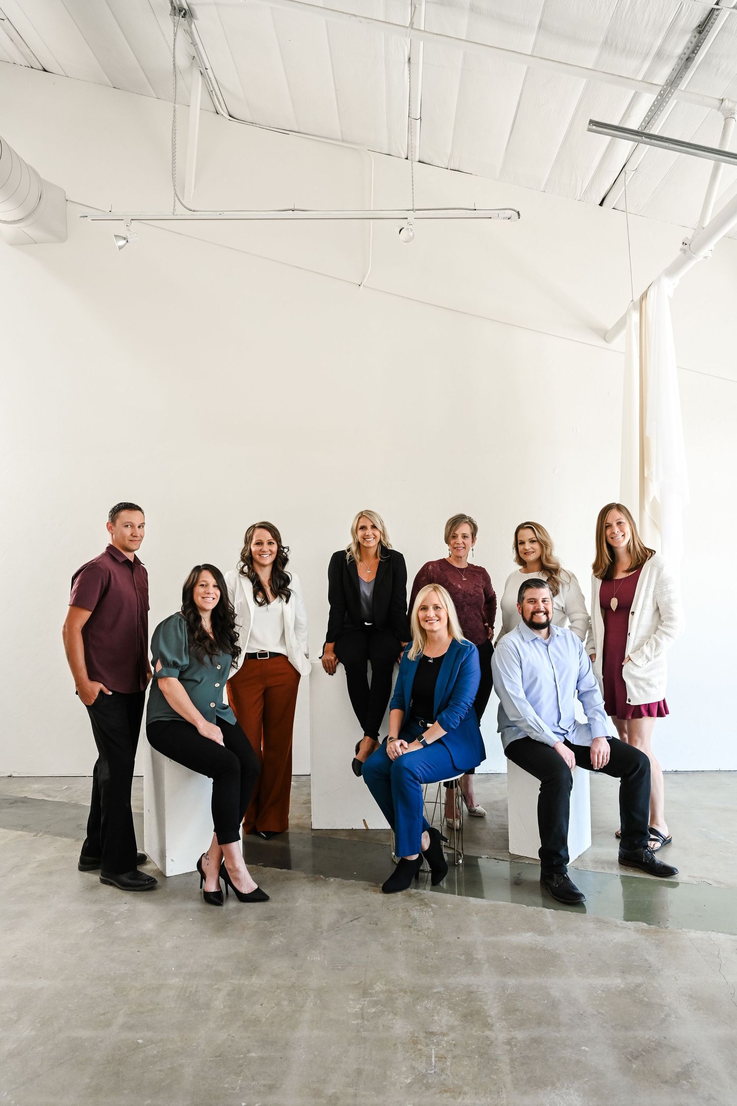 Professional team posing creatively in business attire against white studio background.