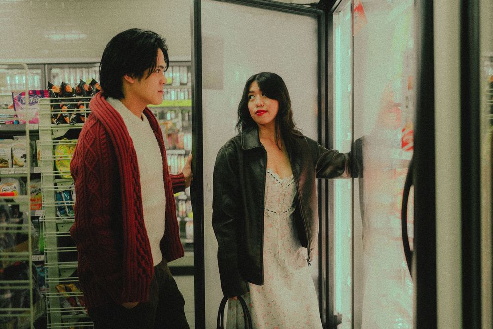 People reflected in storefront window standing in front of convenience store at night.