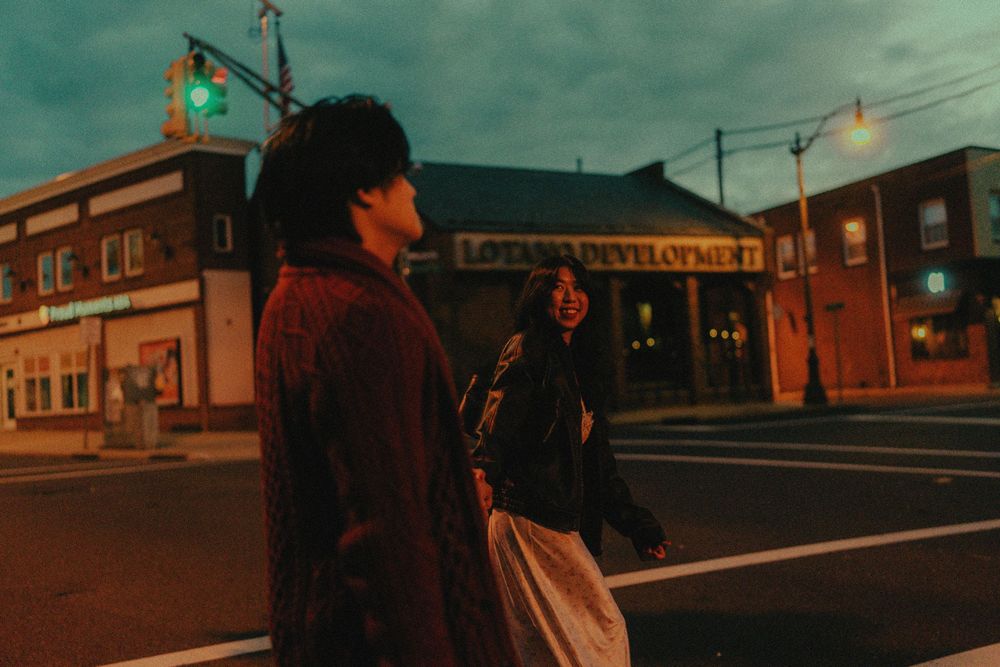 A nighttime city street scene with neon lighting and retro motel signs casting an atmospheric orange glow.