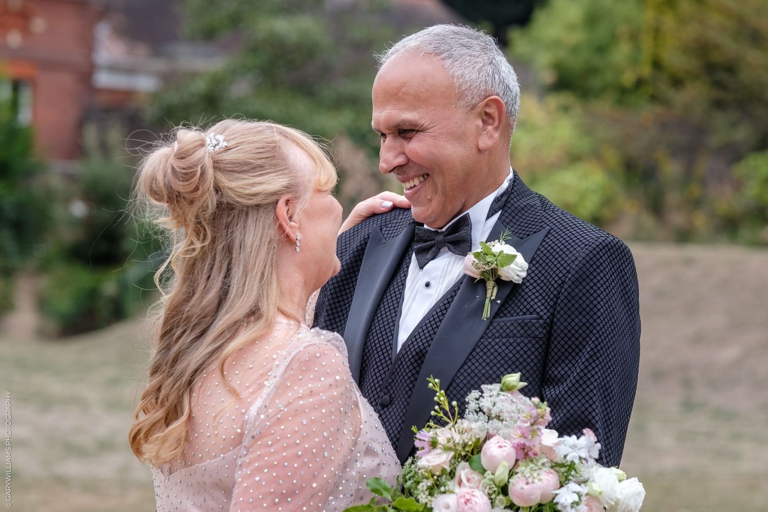 A happy couple embraces outdoors while sharing joyful laughter during their wedding celebration.