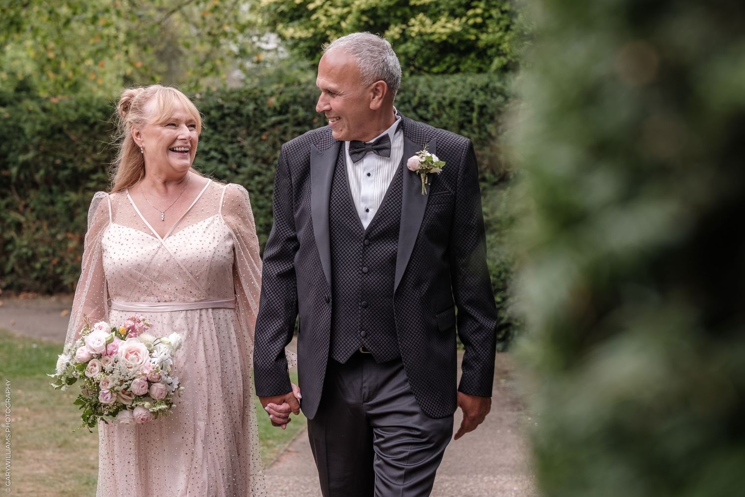 Happy newlyweds share loving moments during their outdoor garden wedding photography session.