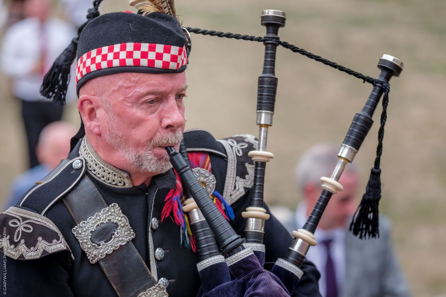 Scottish bagpipers in traditional tartan kilts perform during an outdoor event with their instruments at sunset.