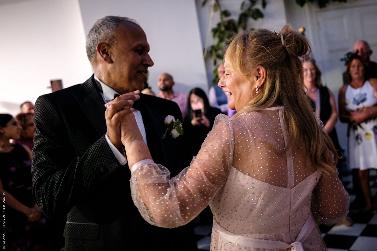Two people dance together during what appears to be a romantic first dance at a wedding reception.