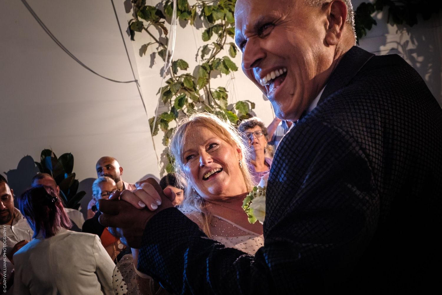 Happy guests socializing at an outdoor gathering with glasses in hand during a casual evening party.
