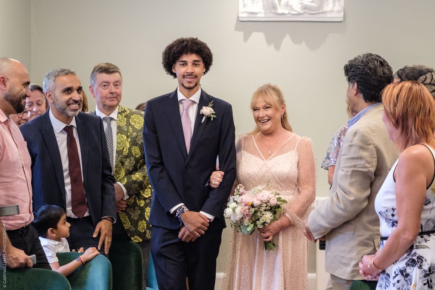 Wedding guests in formal attire gather for a reception celebration in an elegant venue.
